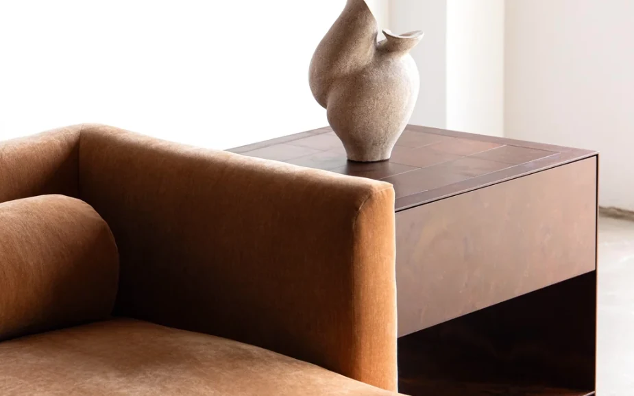 A tan upholstered sofa beside a low cabinet with a ceramic vessel