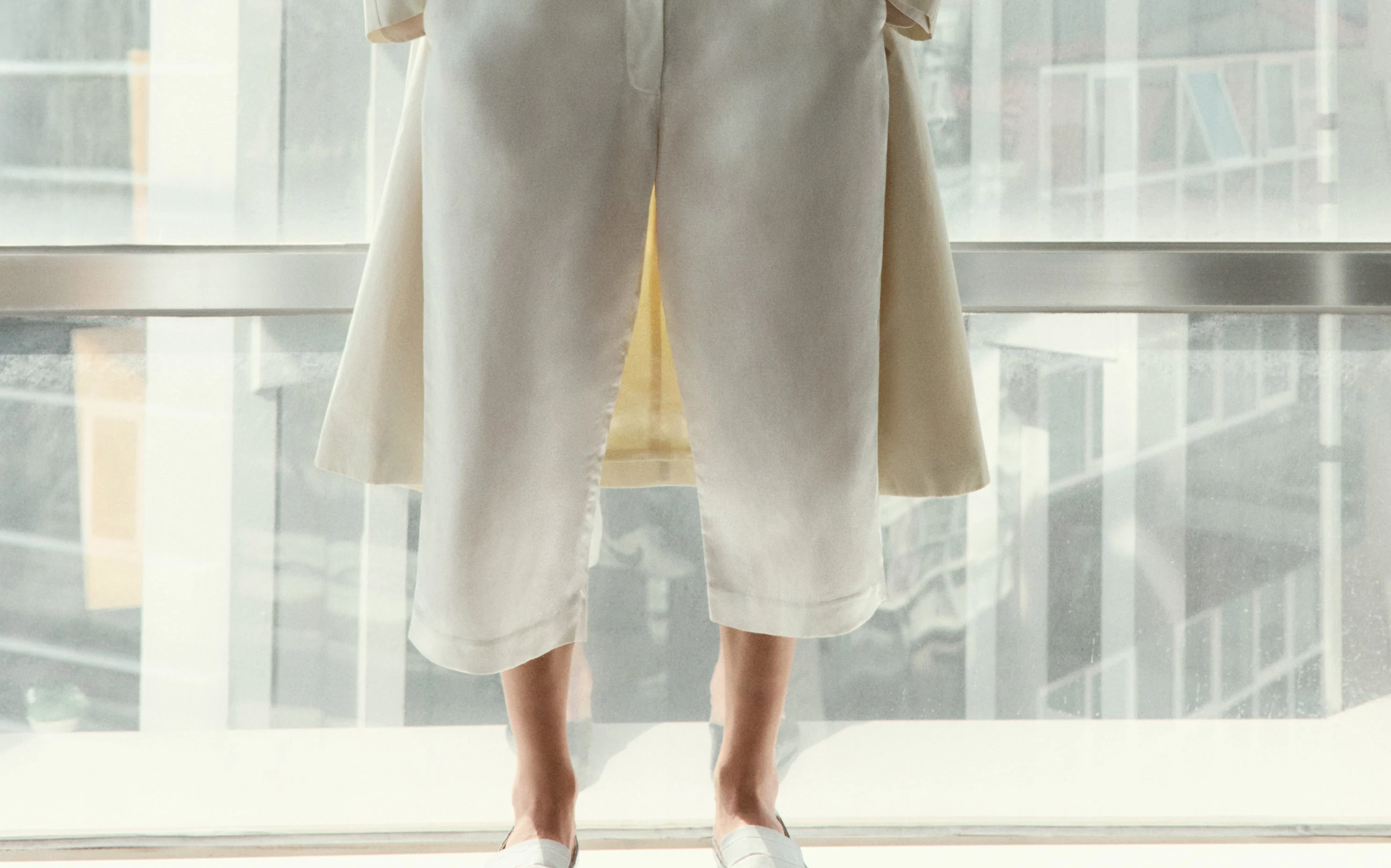 Cropped detail of layered trousers and coat hems against daylight