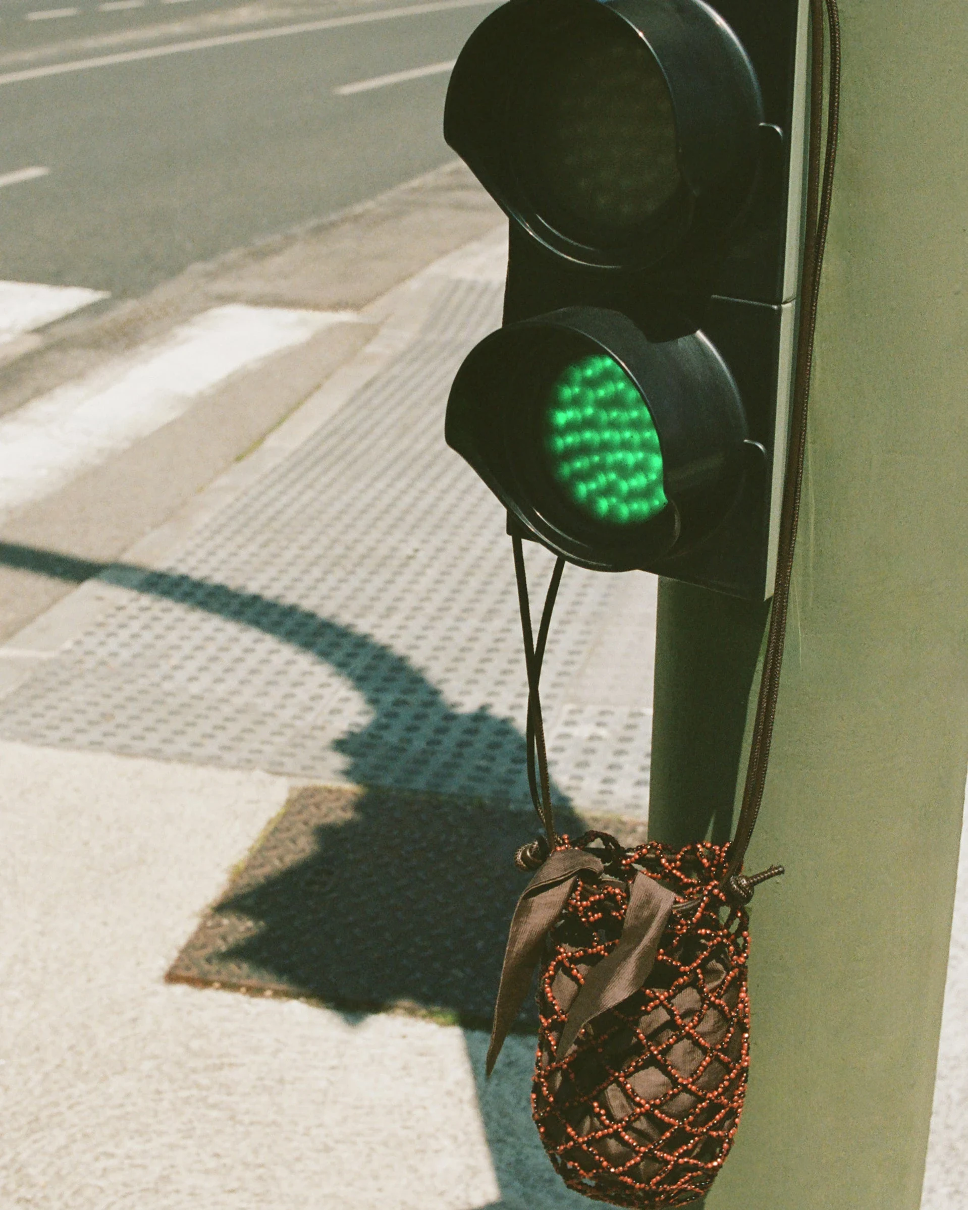 A woven drawstring bag hanging from a street signal post