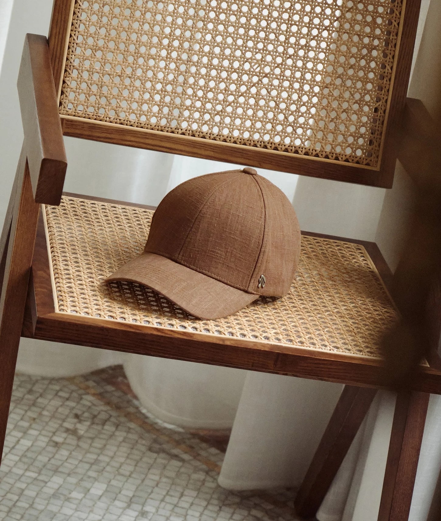 A linen cap resting on a caned wooden chair in a tiled room