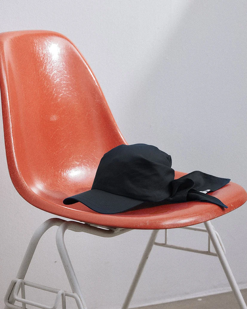 A dark soft cap resting on a moulded orange chair